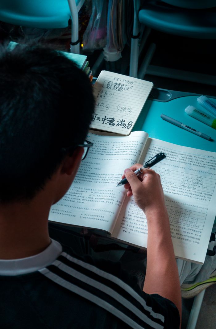 The Art of Drawing Readers In: Your attractive post title goes here A teenager studying hard at a desk with open books and notes indoors.
